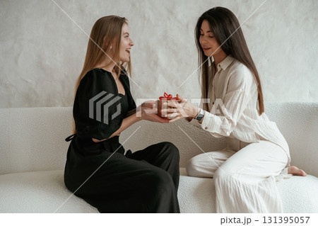 Giving the gift, event. Two happy young female best friends are indoors Giving the gift, event. Two happy young female best friends are indoors 131395057