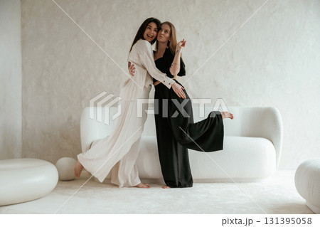 Standing and embracing each other. Two happy young female best friends are indoors Standing and embracing each other. Two happy young female best friends are indoors 131395058