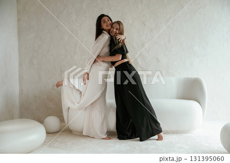 Standing and embracing each other. Two happy young female best friends are indoors Standing and embracing each other. Two happy young female best friends are indoors 131395060