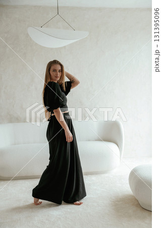 Beautiful young woman in black dress is indoors, posing Beautiful young woman in black dress is indoors, posing 131395096