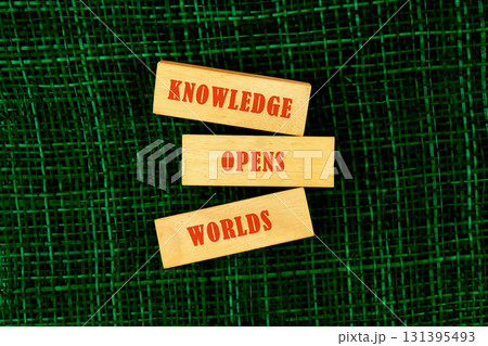 Education,student,university concept. KNOWLEDGE OPENS WORLDS made of wooden blocks on fabric background, top view 131395493