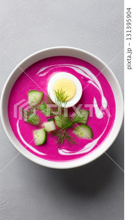 This traditional Lithuanian beet soup showcases vibrant colors with fresh cucumber slices, egg, and herbs in a decorative bowl 131395904