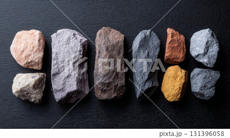 Rock samples show diverse textures and colors on a dark backdrop, emphasizing geological variety 131396058