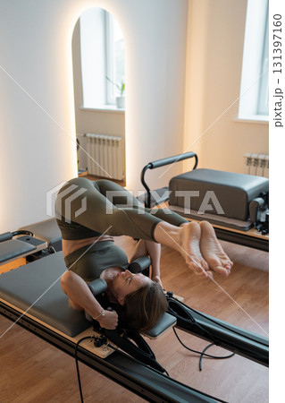 Woman doing Pilates exercise for core and back muscles on Reformer machine with determination and focus on strength body Woman doing Pilates exercise for core and back muscles on Reformer machine with determination and focus on strength body 131397160