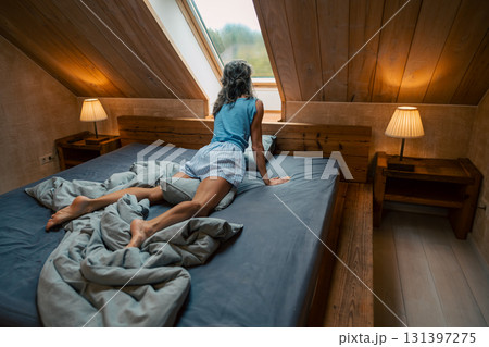A tranquil bedroom scene with a person gazing thoughtfully out the window, enjoying a cozy atmosphere A tranquil bedroom scene with a person gazing thoughtfully out the window, enjoying a cozy atmosphere 131397275