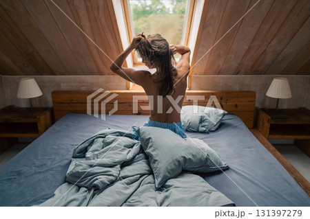 A tranquil morning scene showcasing a person gently awakening in a beautifully softly lit bedroom filled with comfort A tranquil morning scene showcasing a person gently awakening in a beautifully softly lit bedroom filled with comfort 131397279