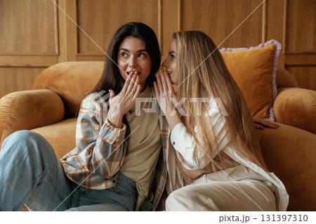 Gossip, telling a secret. Two happy young female best friends are indoors Gossip, telling a secret. Two happy young female best friends are indoors 131397310