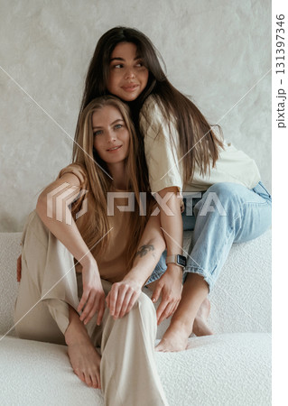 Against white wall. Two happy young female best friends are indoors Against white wall. Two happy young female best friends are indoors 131397346
