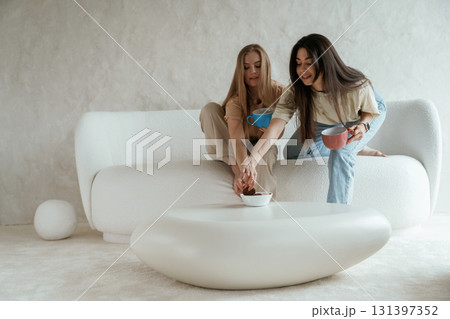 Tea and cookies. Two happy young female best friends are indoors 131397352