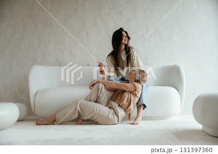 Conception of care. Woman leaning on the legs. Two happy young female best friends are indoors Conception of care. Woman leaning on the legs. Two happy young female best friends are indoors 131397360