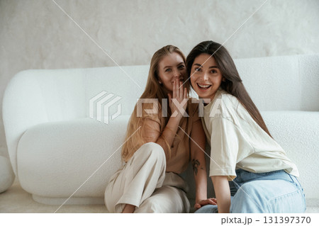 Telling a secret. Two happy young female best friends are indoors Telling a secret. Two happy young female best friends are indoors 131397370