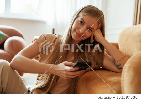 Using smartphone. Beautiful young woman is sitting at home Using smartphone. Beautiful young woman is sitting at home 131397388
