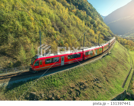 Aerial view of red train in alpine mountains with green meadows 131397441