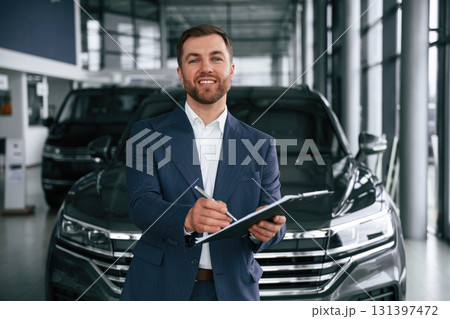 Cheerful salesman. Guy is in a car dealership 131397472