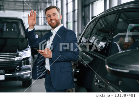 Hello hand gesture. A businessman is in a car dealership 131397481
