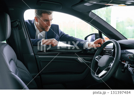 Looking at the automobile. A businessman is in a car dealership Looking at the automobile. A businessman is in a car dealership 131397484