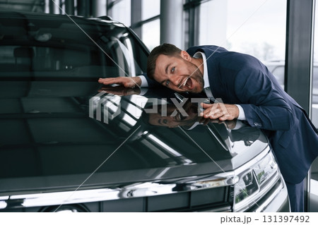 Embracing new automobile. A businessman is in a car dealership 131397492