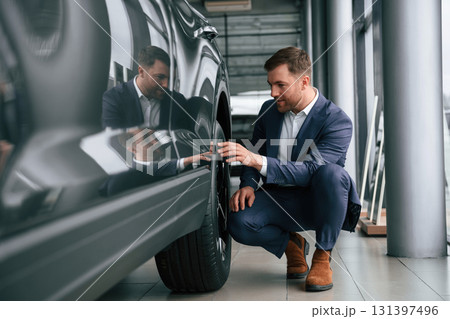Checking the wheel. A businessman is in a car dealership 131397496