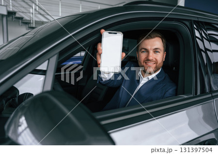 Smartphone with copy space on display. Businessman is in the brand new car 131397504
