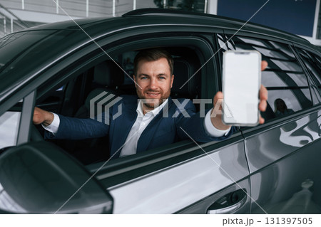 Smartphone with copy space on display. Businessman is in the brand new car 131397505