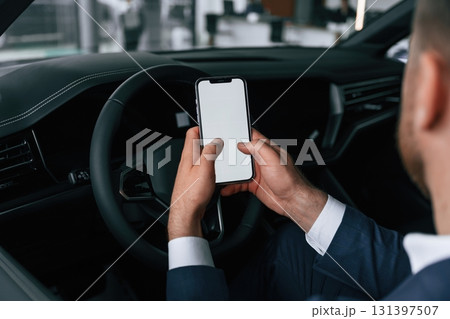 Smartphone with copy space on display. Businessman is in the brand new car Smartphone with copy space on display. Businessman is in the brand new car 131397507