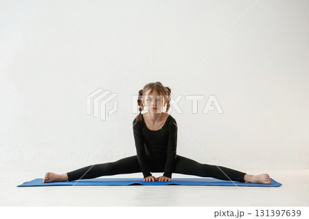 On the twine. Little girl in yoga clothes is on the fitness mat 131397639