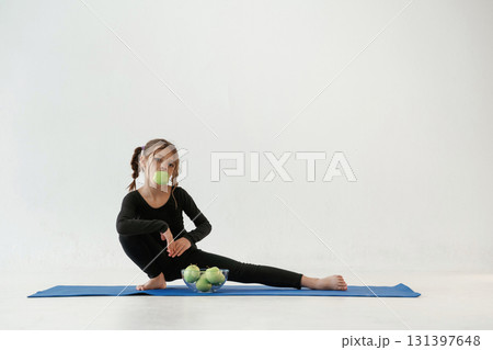 Healthy eating, green apples. Little girl in yoga clothes is on the fitness mat Healthy eating, green apples. Little girl in yoga clothes is on the fitness mat 131397648