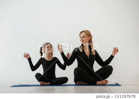 Mother and little daughter are in fitness clothes on yoga mat Mother and little daughter are in fitness clothes on yoga mat 131397678