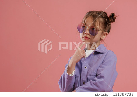 In stylish sunglasses. Cute little girl is against pink background In stylish sunglasses. Cute little girl is against pink background 131397733