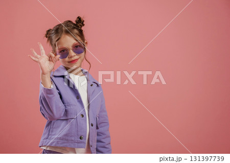Fine hand gesture. Cute little girl is against pink background Fine hand gesture. Cute little girl is against pink background 131397739