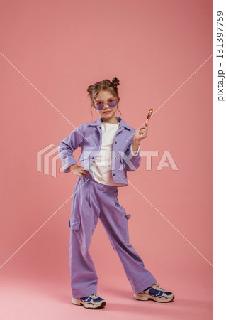 Colorful sweet candy in hand. Cute little girl is against pink background Colorful sweet candy in hand. Cute little girl is against pink background 131397759