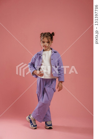 Standing and posing. Cute little girl is against pink background 131397786