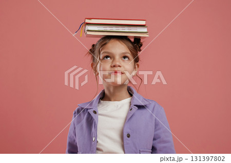 Notepads on the head. Cute little girl is against pink background 131397802