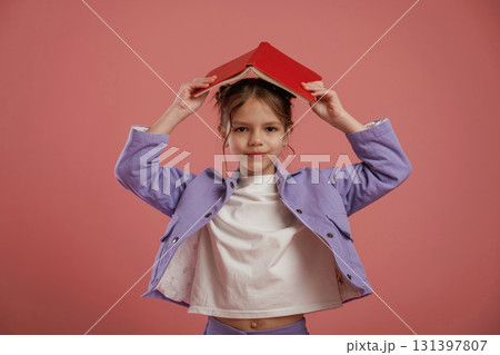 Notepads on the head. Cute little girl is against pink background Notepads on the head. Cute little girl is against pink background 131397807