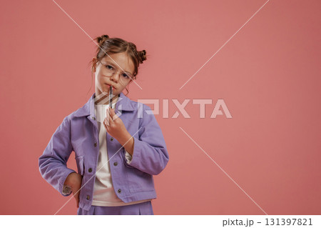 Thinking, holding pen, smart pupil. Cute little girl is against pink background Thinking, holding pen, smart pupil. Cute little girl is against pink background 131397821
