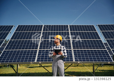 Black notepad in hands. Engineer with photovoltaic solar panels outdoors at daytime Black notepad in hands. Engineer with photovoltaic solar panels outdoors at daytime 131398125