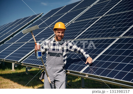 Procedure of cleaning the surface. Engineer with photovoltaic solar panels outdoors at daytime Procedure of cleaning the surface. Engineer with photovoltaic solar panels outdoors at daytime 131398157