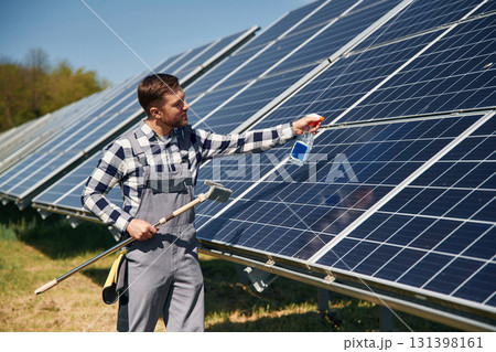 Procedure of cleaning the surface. Engineer with photovoltaic solar panels outdoors at daytime Procedure of cleaning the surface. Engineer with photovoltaic solar panels outdoors at daytime 131398161