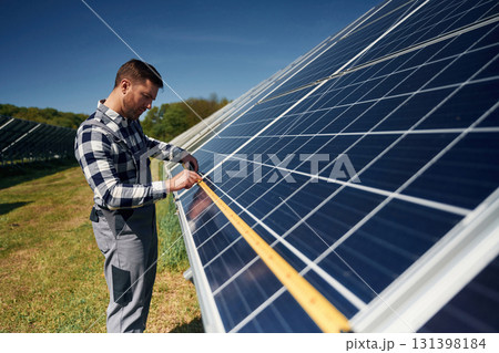 Measuring the width by tape. Engineer with photovoltaic solar panels outdoors at daytime Measuring the width by tape. Engineer with photovoltaic solar panels outdoors at daytime 131398184