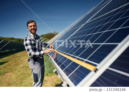 Measuring the width by tape. Engineer with photovoltaic solar panels outdoors at daytime 131398186