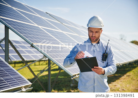 Professional adult engineer with photovoltaic solar panels outdoors at daytime Professional adult engineer with photovoltaic solar panels outdoors at daytime 131398491