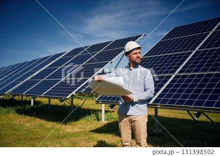 Reading the plan on paper. Engineer with photovoltaic solar panels outdoors at daytime Reading the plan on paper. Engineer with photovoltaic solar panels outdoors at daytime 131398502