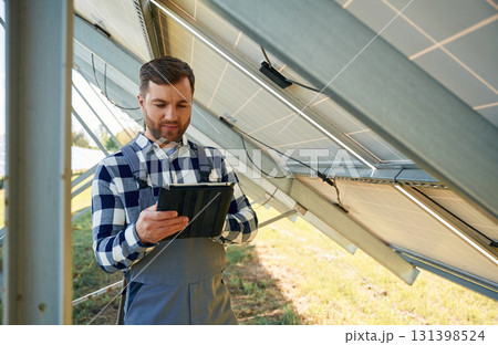 Under the photovoltaic solar panel and with digital tablet. Engineer outdoors at daytime 131398524