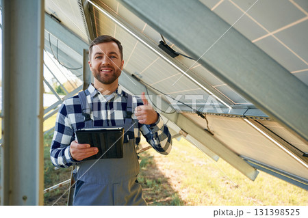 Under the photovoltaic solar panel and with digital tablet. Engineer outdoors at daytime 131398525
