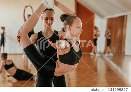Under the supervision of a professional trainer. Group of female kids practicing athletic exercises together indoors Under the supervision of a professional trainer. Group of female kids practicing athletic exercises together indoors 131399297