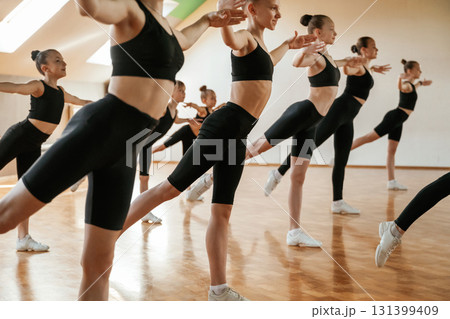 Active training. Group of female kids practicing athletic exercises together indoors Active training. Group of female kids practicing athletic exercises together indoors 131399409