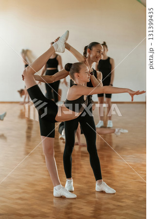 Controlling the process by coach. Group of female kids practicing athletic exercises together indoors 131399435