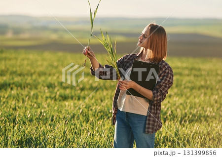 Scientist is checking the plant. Young woman is on the beautiful agricultural field at daytime 131399856