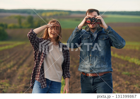 Using binoculars. Lovely beautiful couple are together on the agricultural field 131399867