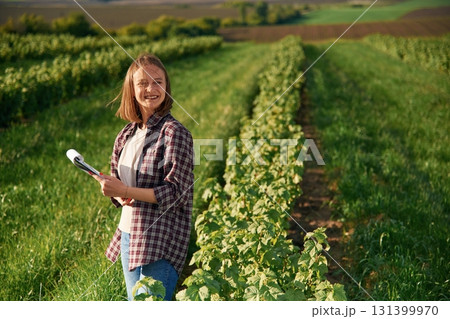 Sunny weather, standing. Young woman is on the beautiful agricultural field at daytime Sunny weather, standing. Young woman is on the beautiful agricultural field at daytime 131399970